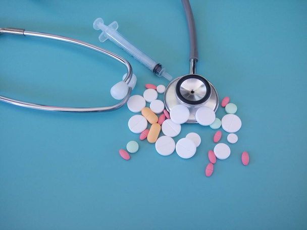 таблетки и стетоскоп изолированы на голубом фоне - Фото, изображение