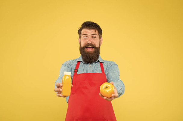 男ひげのシェフは有機天然トマトとボトルイエローの背景を保持しています。ベジタリアンの栄養。スムージー・ドリンク。フレッシュジュース。スムージーを絞る。新鮮なビタミンを提供します。ヒップスタースムージー飲料 - 写真・画像
