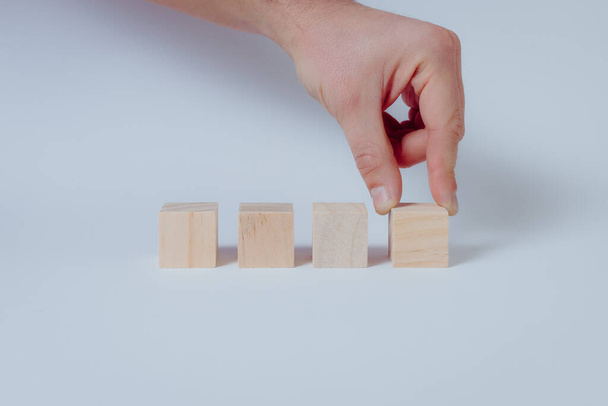 Close up of hand completing the series wooden cubes. White background, concept - Фото, изображение