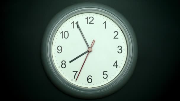 White wall clock tells the time. Rotation of the short and long hands of the clock. On the black background. - Filmati, video