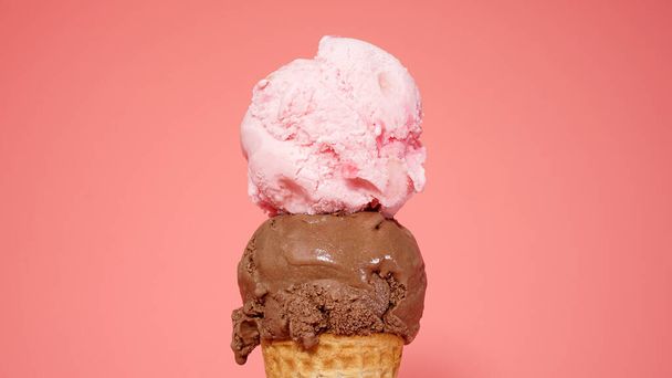  上にイチゴのアイスクリームピンクの背景に隔離されたチョコレートアイスクリームコーン.     - 写真・画像