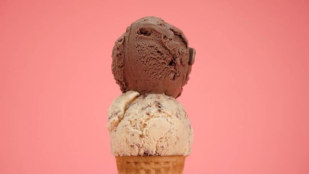 Crème glacée au chocolat sur le dessus Cuillère de pépites de chocolat dans un cône de gaufre isolé sur fond rose - Photo, image
