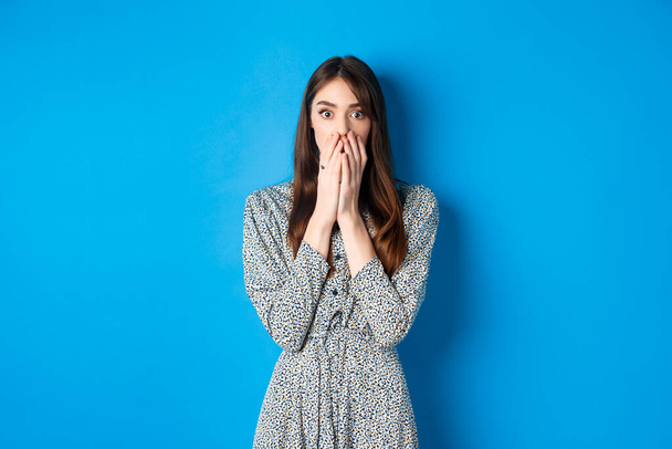 Shocked european girl gasping and covering mouth with hands, witness something and look startled, standing worried on blue background - Fotoğraf, Görsel