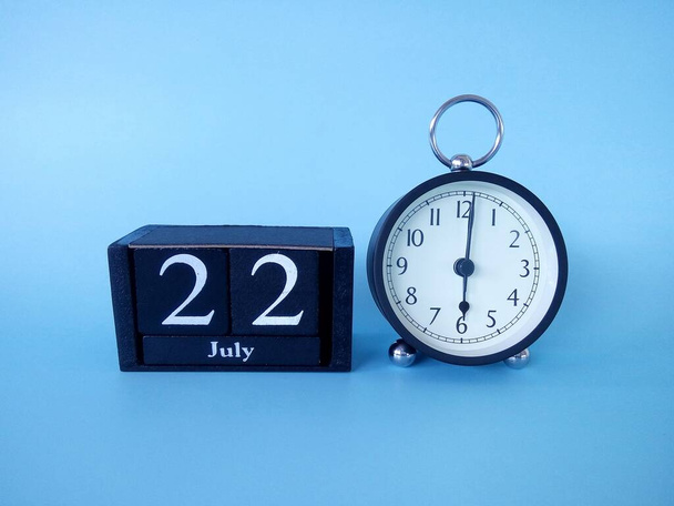 Reloj despertador aislado sobre fondo azul con fecha - Foto, imagen