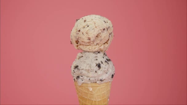 Time lapse, fusión de dos sabores de helado en el cono. Después de derretirlo lentamente salió del cono. Sobre el fondo rosa - Imágenes, Vídeo