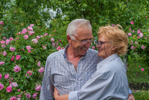 Улыбаясь, счастливая старшая леди и мужчина обнимают смех. Весна или летний солнечный день. - Фото, изображение