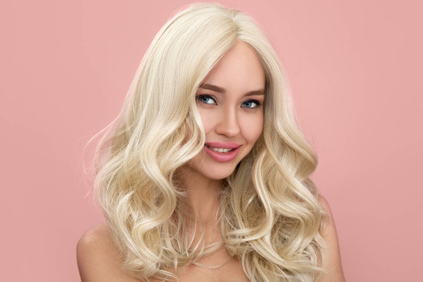 portret van gelukkige jonge blonde vrouw. Roze achtergrond - Foto, afbeelding
