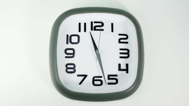 Uhr mit weißem Zifferblatt mit grünem Rand um 11.28 Uhr, der Hintergrund auf der Rückseite ist weiß. - Filmmaterial, Video
