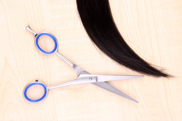 Long brown hair and scissors on wooden background - Фото, зображення