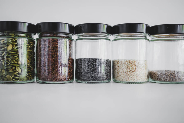 simple food ingredients concept, seed jars with sesame poppy pupmkin chia and flax seeds as important nutrient sources for nutrition shot on white background - Fotó, kép