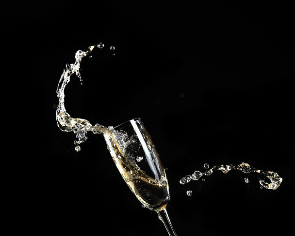 Glass of champagne with splash, on black background - Photo, Image