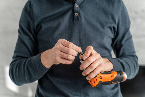 Pohled zblízka na ruce dospělého bělocha držícího elektrický šroubovák - Fotografie, Obrázek