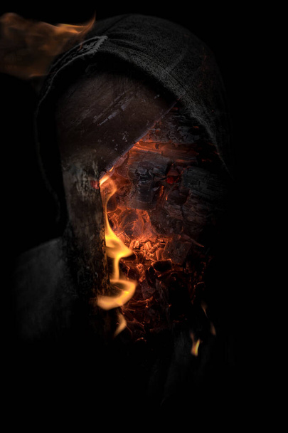 Απόκριες ανατριχιαστικός άνθρωπος στη σκιά με κουκούλα και καύση πορτρέτο φωτιά. δαιμονική κατοχή με λαμπερά κόκκινα μάτια από την κόλαση έννοια - Φωτογραφία, εικόνα