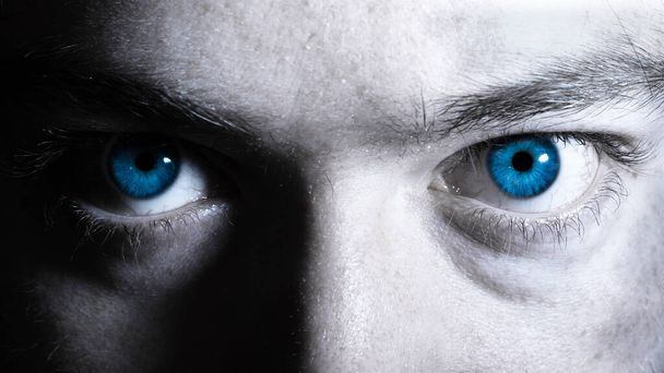 Bright blue eyes of a man close up black and white portrait. Vibrant colorful dramatic eyes background. Window to the soul concept - Photo, Image