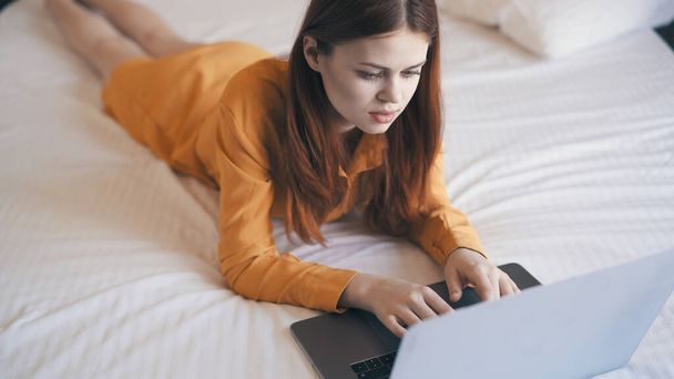 femme se trouve dans le lit en face du travail de dactylographie ordinateur portable à la maison - Photo, image