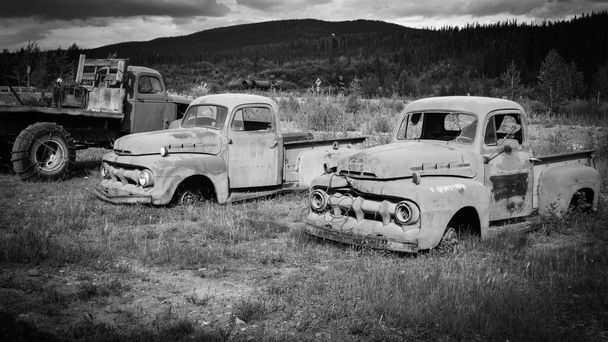 Vieux camions abandonnés dans un champ envahi. USA 1943 Base aérienne d'Eielson. Véhicules militaires historiques et vintage fond noir et blanc - Photo, image