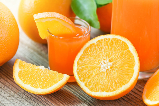 Świeży sok pomarańczowy w szklance z pomarańczowymi owocami na drewnianym tle, zdrowe owoce i plasterek pomarańczy  - Zdjęcie, obraz