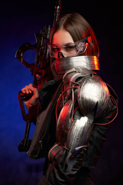 Donna futuristica con occhiali e fucile in fondo blu scuro - Foto, immagini