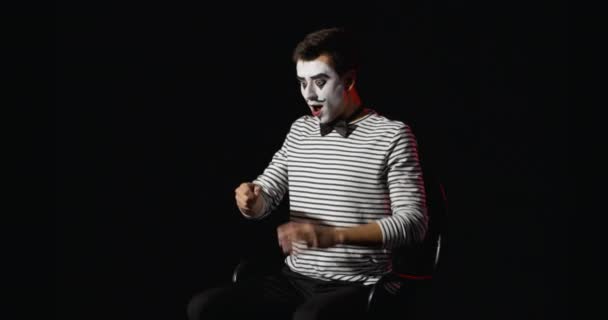 Miming male artist eating imaginary banana on dark background - Footage, Video