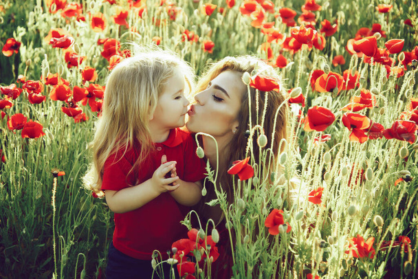 Cute girl and little boy or child in field of poppy. Spring kiss. - 写真・画像