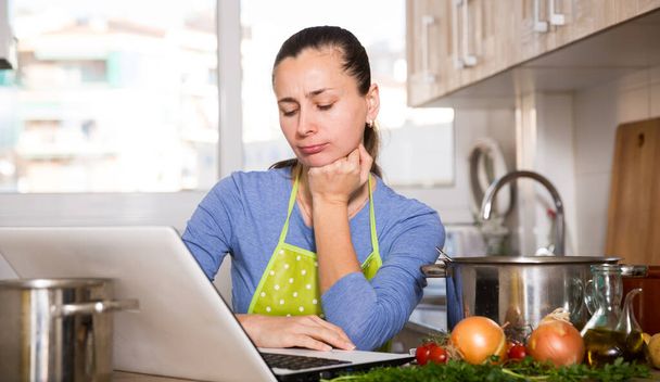 Upset young woman reading recipe on laptop screen - Zdjęcie, obraz