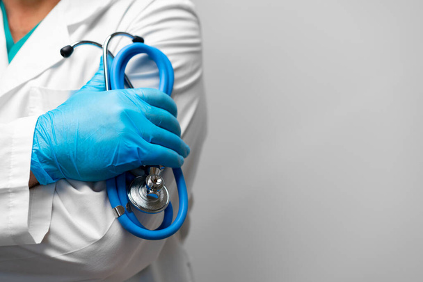 Doctor holding a stethoscope with arms crossed wearing blue gloves - Foto, Imagem