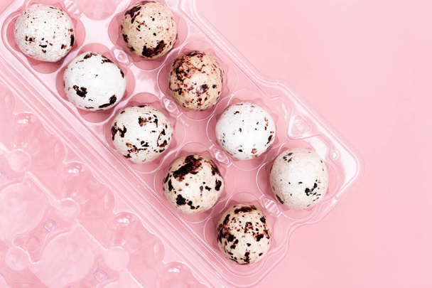 Chocolate Quail eggs plastic package on pastel background. Small pink egg, spring Easter holiday - Fotoğraf, Görsel
