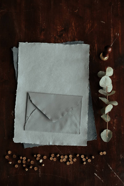 leerer Umschlag mit einem Geschenk und einem Stück Papier auf einem Holzgrund - Foto, Bild