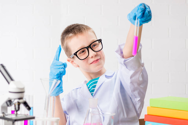 Egy mikroszkópos iskolás fiú kémcsövekben vizsgálja a vegyi anyagokat, kísérleteket végez - egy fehér hátterű portrét. A coronavirus laboratóriumi vizsgálatának koncepciója - Fotó, kép