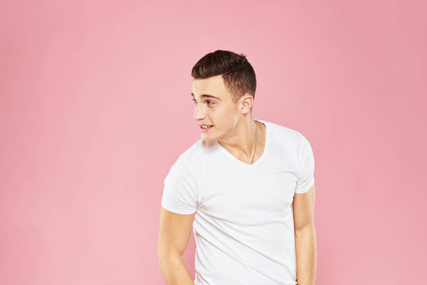 Wesoły przystojny mężczyzna w białej koszulce emocje różowy odizolowane tło - Zdjęcie, obraz