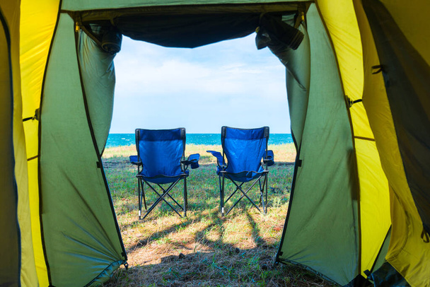θέα στη θάλασσα και καρέκλες από τη σκηνή του κάμπινγκ - concept vacation, camping, χαλάρωση - Φωτογραφία, εικόνα