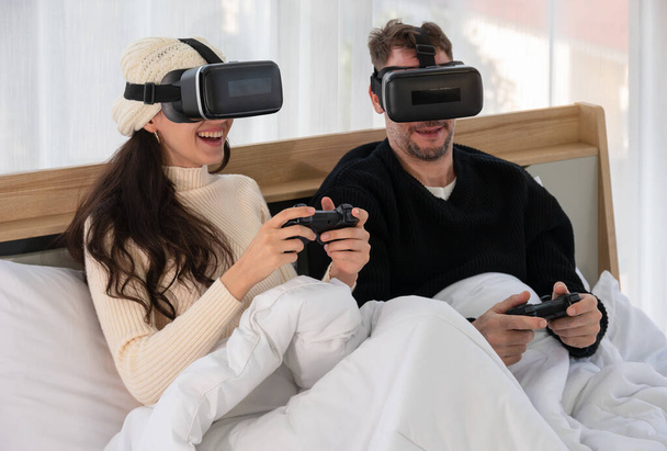 Happy couple wearing Virtual reality headset and having fun while playing VR games together in be - Photo, Image
