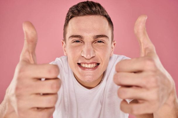 веселий чоловік у білій футболці посміхається емоції крупним планом рожевий фон студії
 - Фото, зображення