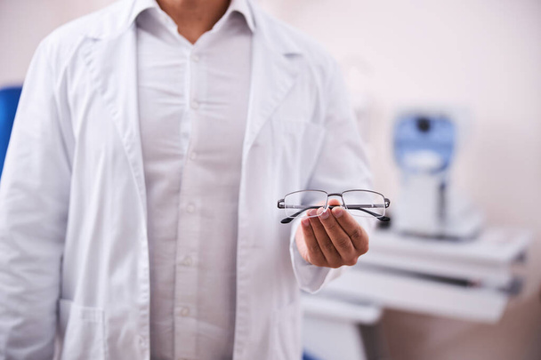 Консультант по очкам в лабораторном халате предлагает модные очки - Фото, изображение