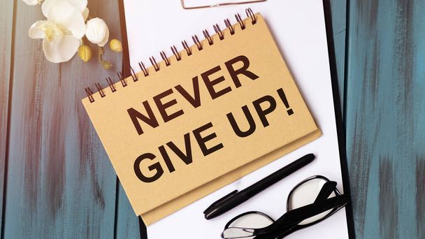 Notebook written with Never Give Up word on wooden background. Business Concept. - Foto, Imagen