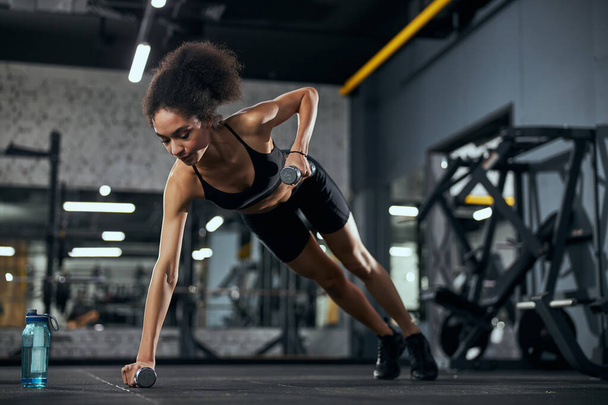 Добрая международная спортсменка занимается фитнесом в тренажерном зале - Фото, изображение