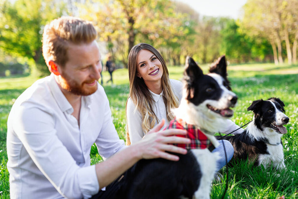 Young couple in love walking and enjoy time in park with dogs. Dog people adoption concept - Foto, Bild