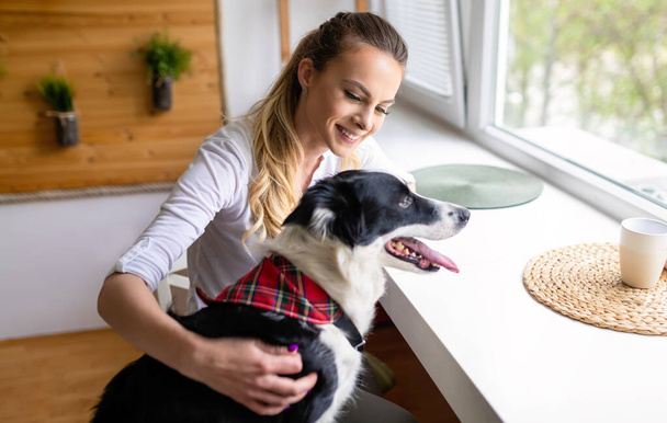 Happy young woman playing with her dog at home. People pet lifestyle concept - Fotó, kép