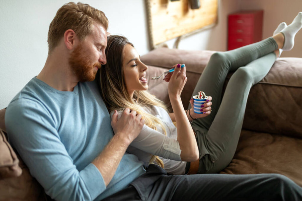 Young couple in love watching TV on a sofa at home. People, home, relaxtion concept - Foto, imagen