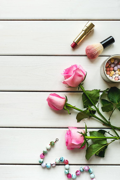 Σύνθεση με make-up, τριαντάφυλλα, κολιέ και φωτοτυπίες σε λευκό ξύλινο φόντο - Φωτογραφία, εικόνα