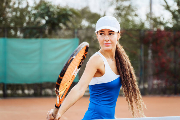 Professional tennis player doing sport on the court. She's about to hit the ball, suspended in the air, with racket. Tennis player in action. It takes a lot of energy and strength to win a match. - Photo, Image
