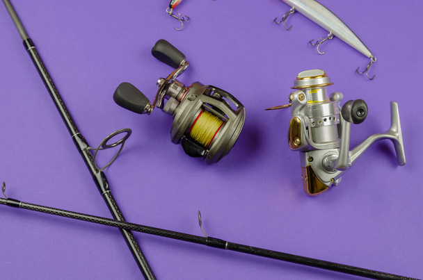 Fishing rod fly fishing reel, baitcasting reel and baits on blue background. Fishing, tackle, sport. Selective focus. - 写真・画像