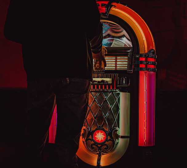 Male hand pushing buttons to play song on old Jukebox, selecting records - Fotografie, Obrázek