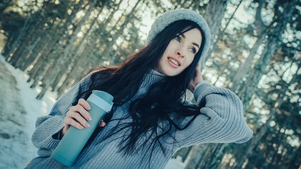 Jeune femme dans une forêt de pins avec une tasse thermo dans les mains - Photo, image