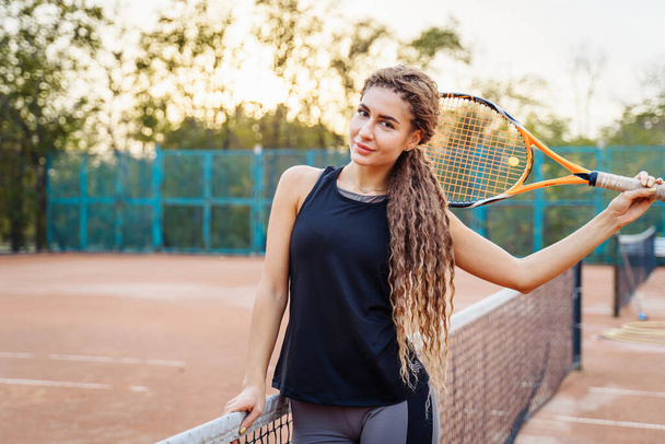 A full-length portrait of a beautiful, cheerful tennis player standing on an open court looking at the camera. Smiling happily. Copy space. Place for an inscription. Sports shooting for the magazine. - Photo, Image
