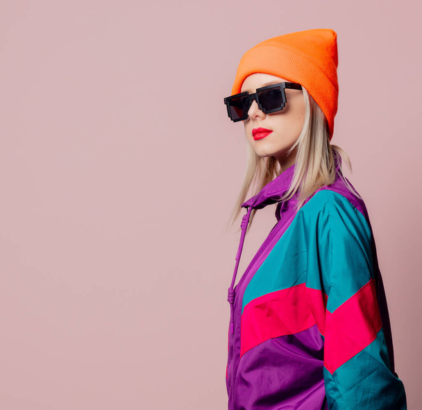 Style girl in 80s sportsuit and sunglasses on pink background - Fotó, kép