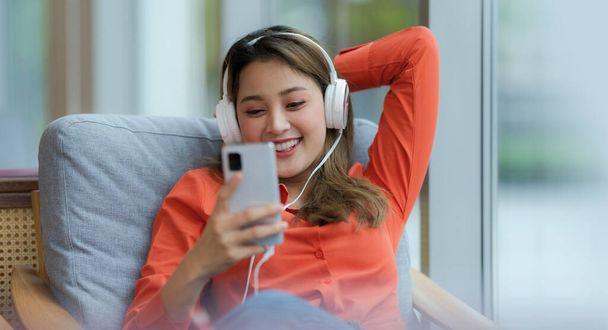 Portrait of young beautiful woman enjoying the music with smiling face sitting near window in creative office or cafe - Foto, Imagen