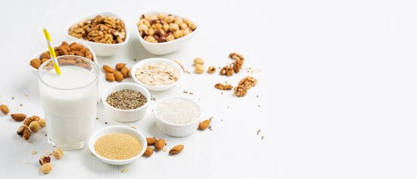 Fresh vegan alternative nut milk in glass and ingredients on white wooden background. Healthy plant food concept. Selective focus, copy space. - Photo, Image
