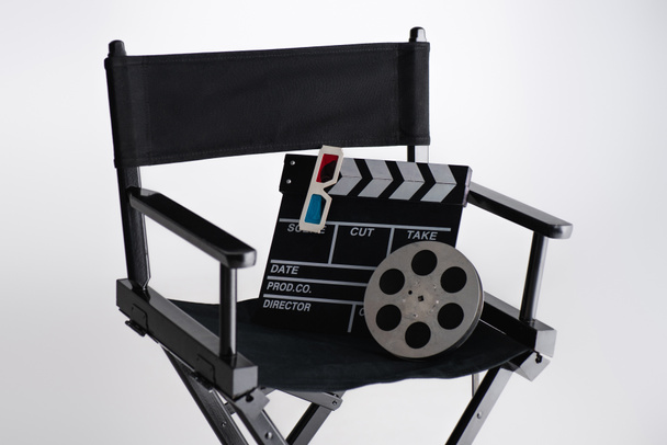 πλακέτα, τρισδιάστατα γυαλιά και πηνίο ταινιών σε καρέκλα κινηματογραφιστή σε λευκό, κινηματογραφική έννοια - Φωτογραφία, εικόνα