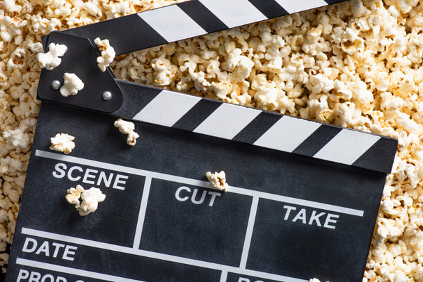 top view of clapperboard on salty popcorn, cinema concept - Photo, Image